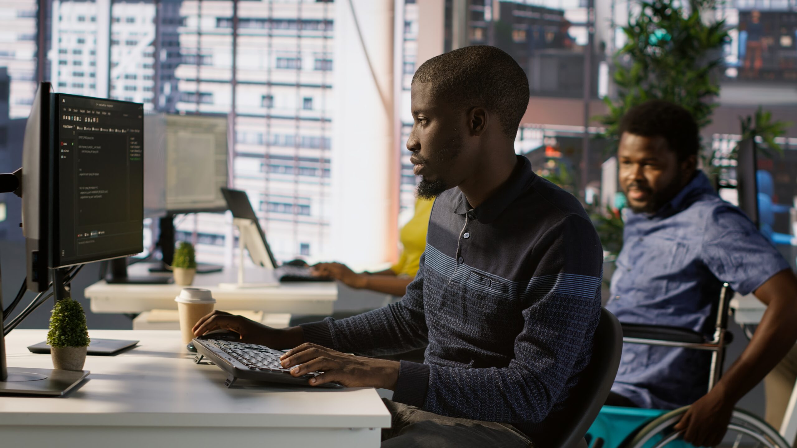 Programmer doing software debugging, asking for help from smiling team leader in wheelchair. Employee fixing coding mistakes, being assisted by cheerful manager with disability, camera A